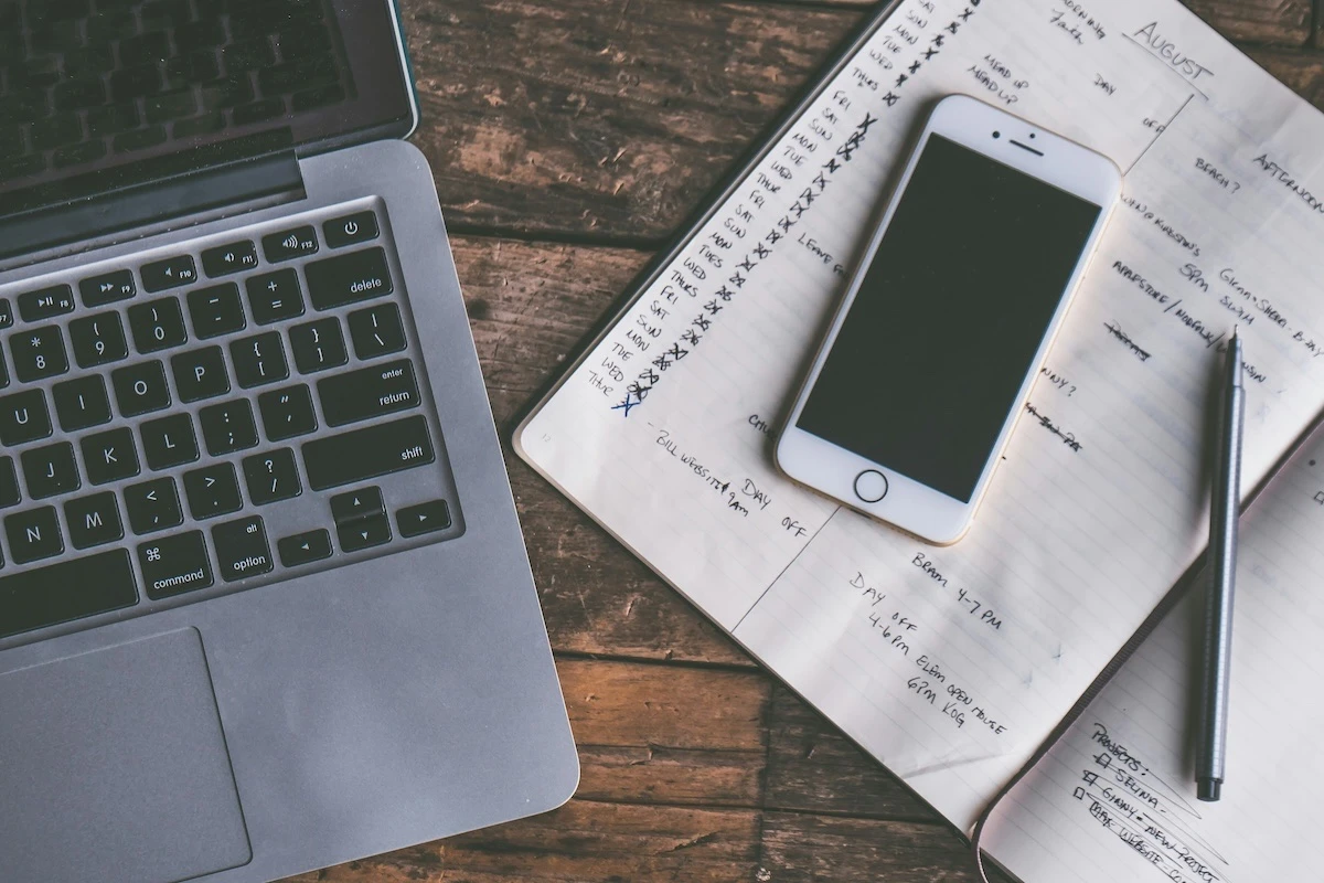 A laptop, phone and a to-do list on a desk