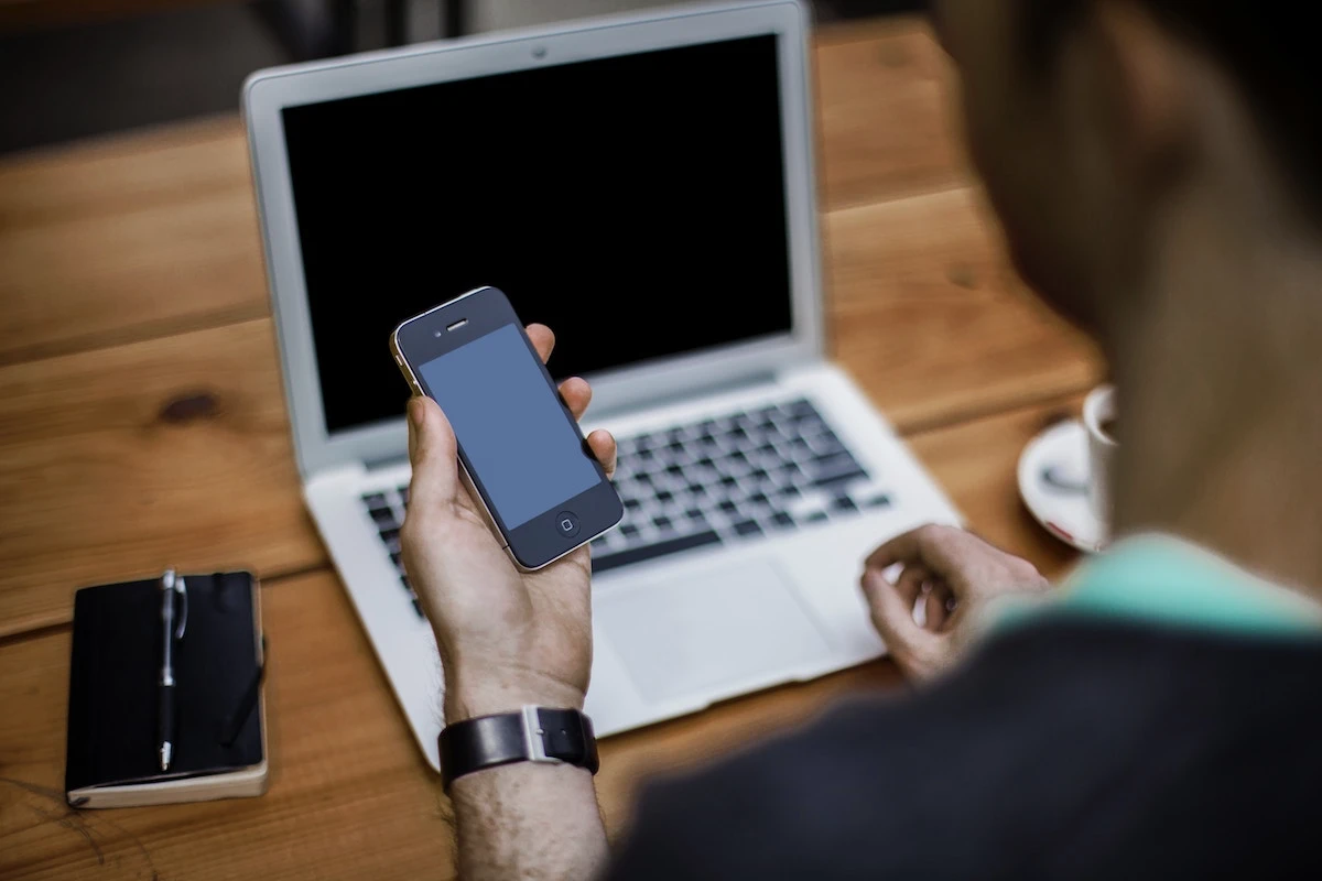 Someone holding a phone in front of an open laptop